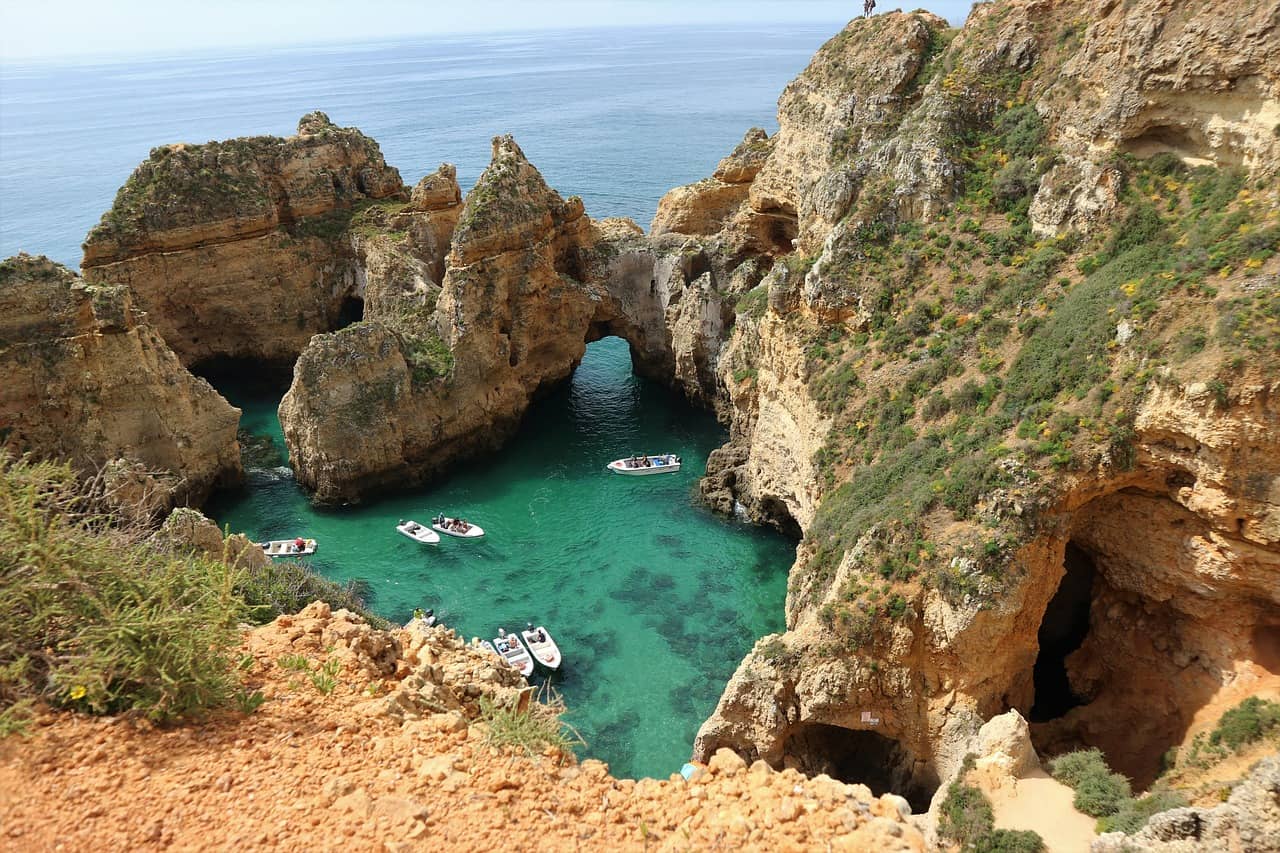 Cliffs in the Algarve with smaller boats in the water.