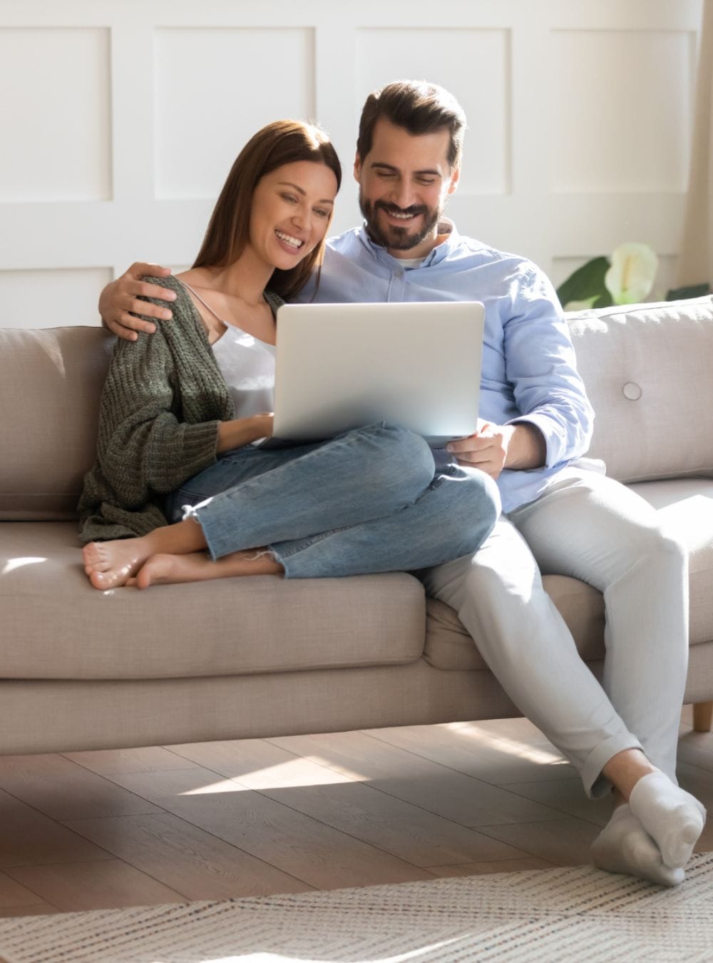 A couple sitting on the couch with a laptop.