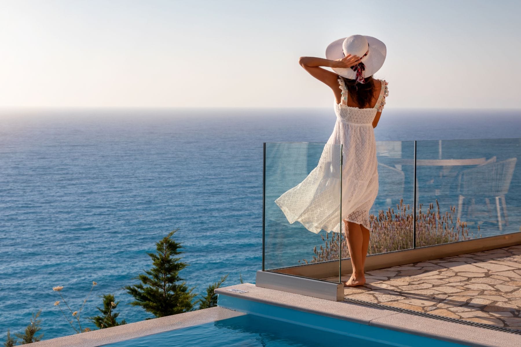 Eine Frau auf einem Balkon, die auf das Meer schaut.