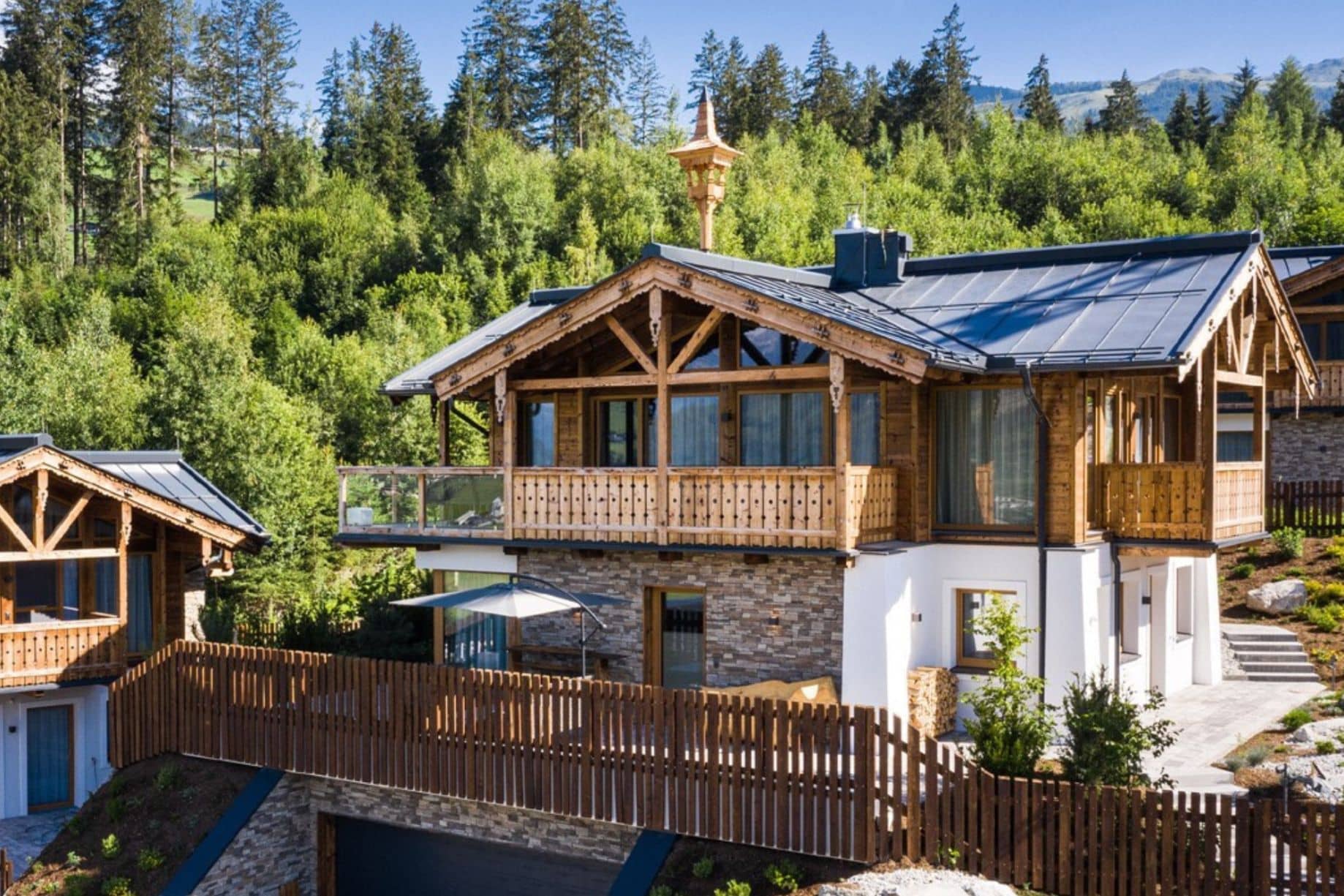 Luxus-Chalet in den Alpen: Moderne Bergvilla aus Holz und Stein mit großzügigem Balkon und Waldblick.
