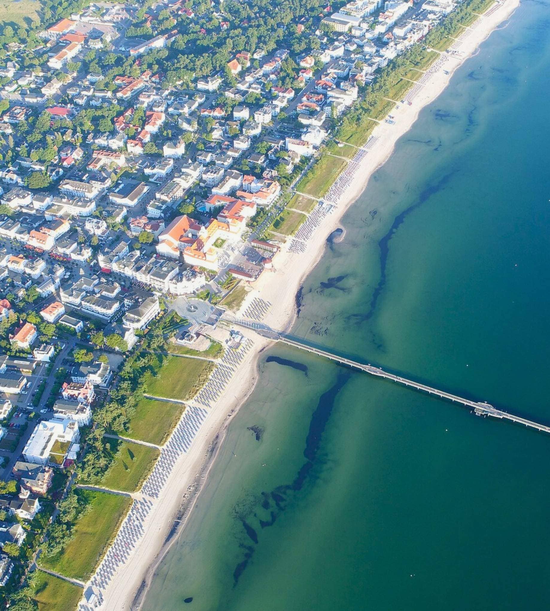 Luxusimmobilien an der Ostsee: Luftaufnahme der Seebrücke Binz, des Sandstrandes und der historischen Bäderarchitektur auf Rügen.