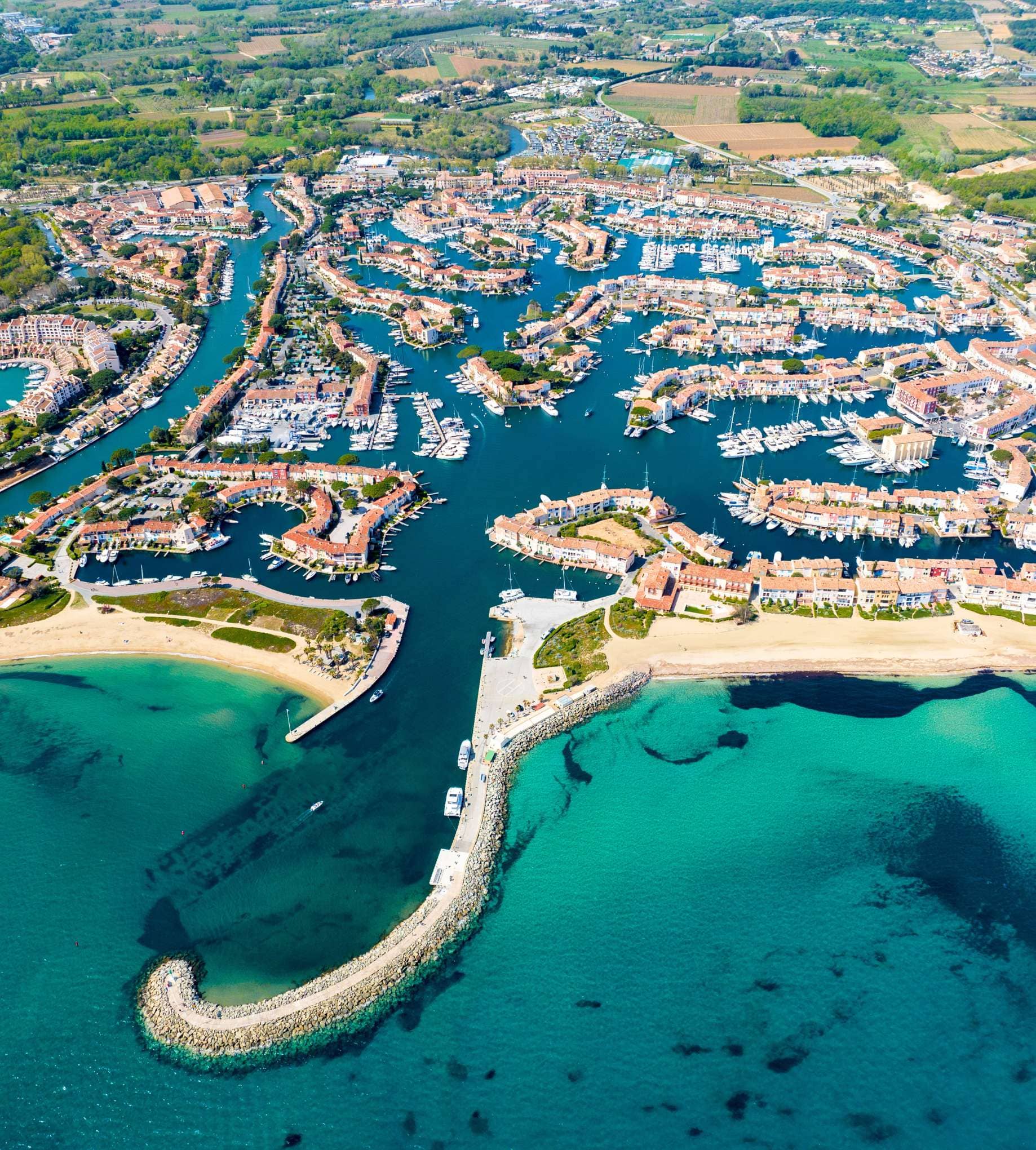 Luxe vastgoed in Port Grimaud, Frankrijk: Luchtfoto van de jachthaven, kleurrijke villa's en het zandstrand aan de Côte d'Azur.